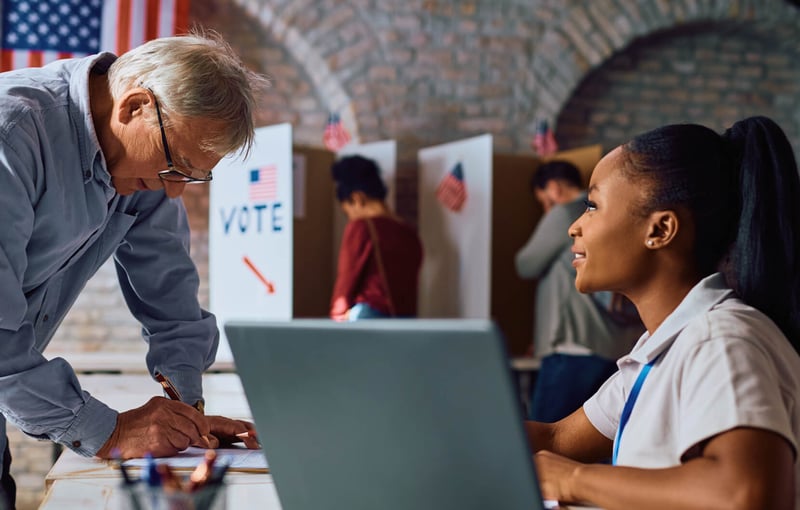 Poll worker assisting an older gentlemen to vote
