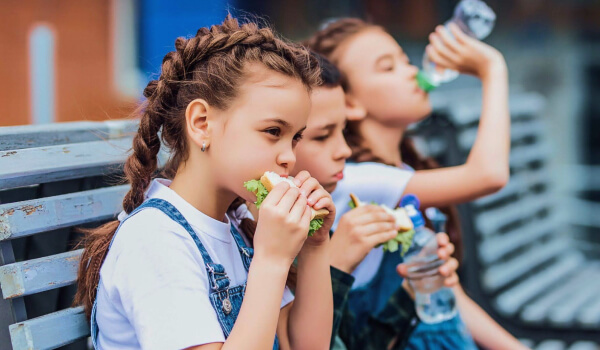 Case study cover image of three young kids eating school lunch